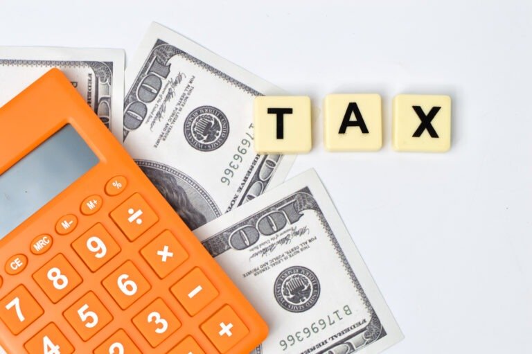 Money banknotes, calculator and scrabble letters with word TAX.