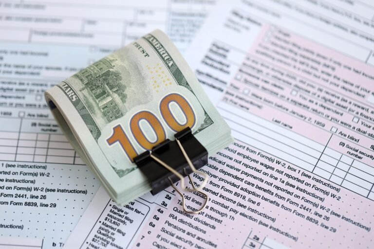 Big amount of United States dollar bills on table with tax return form close up